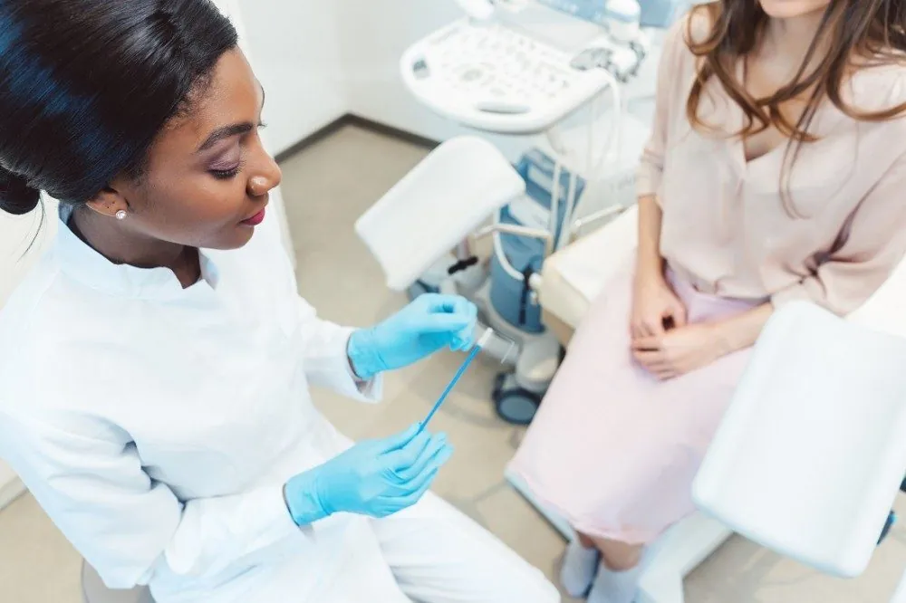 A clinician preparing a swab for a test while a patient sits nearby