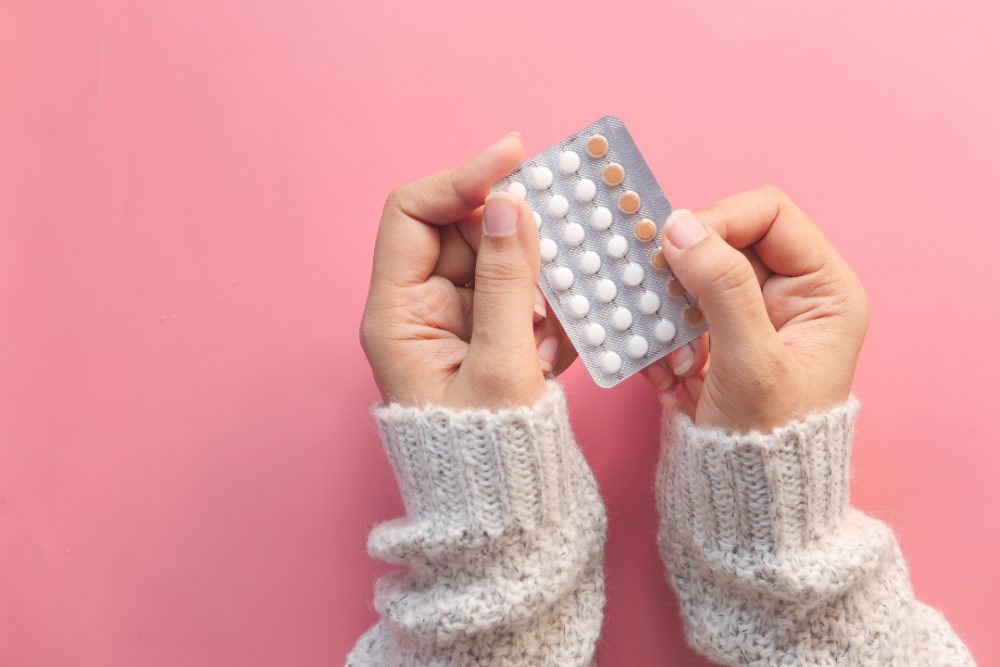 A woman holding a blister pack of birth control pills