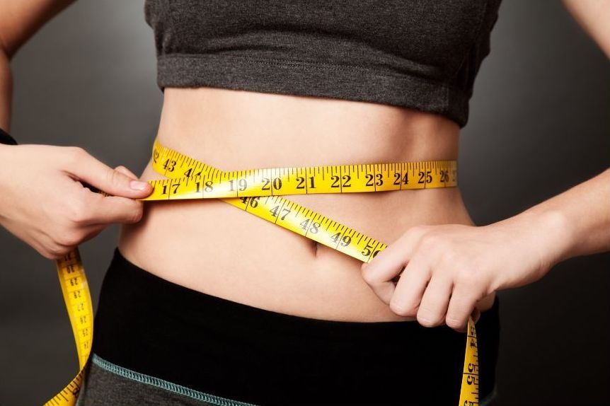 A woman measuring her waist with a tape measure