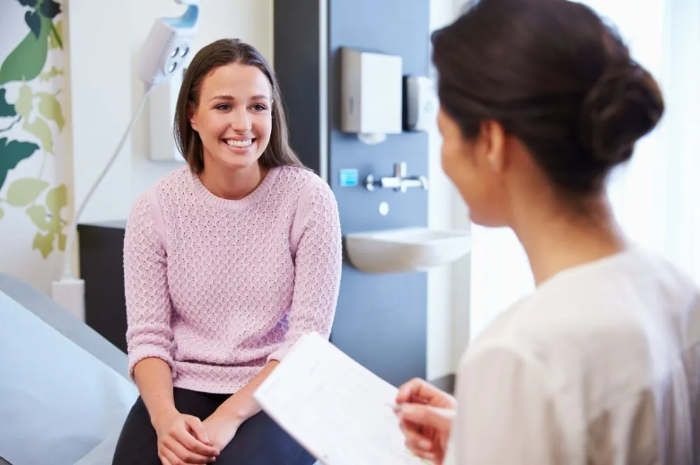 A smiling woman talking with her clinician in a consultation room