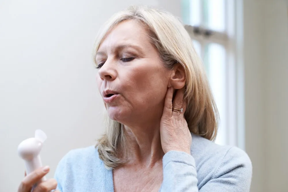 A woman in her fifties fanning herself during a hot flash