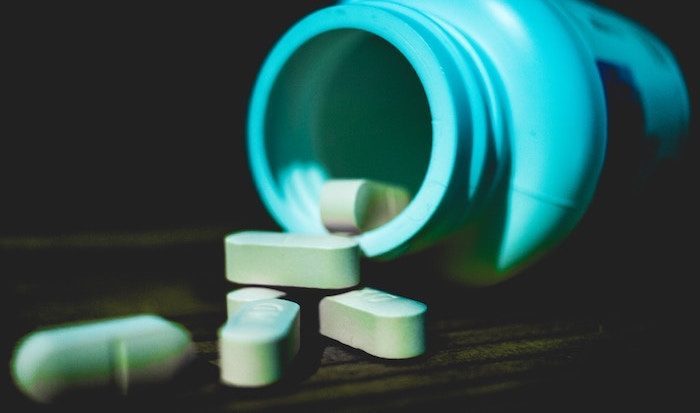 A bottle of pills spilling onto a dark table