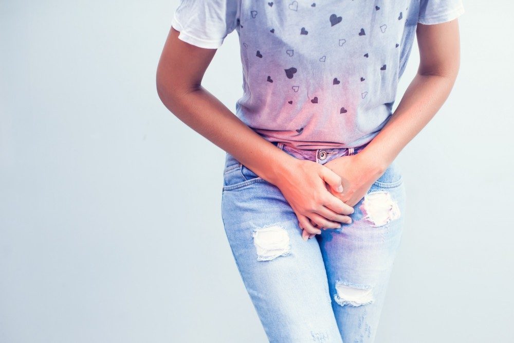 A woman in a purple shirt pressing her hands to her lower abdomen